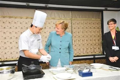 默克尔在成都一家餐厅学习川菜宫保鸡丁的做法