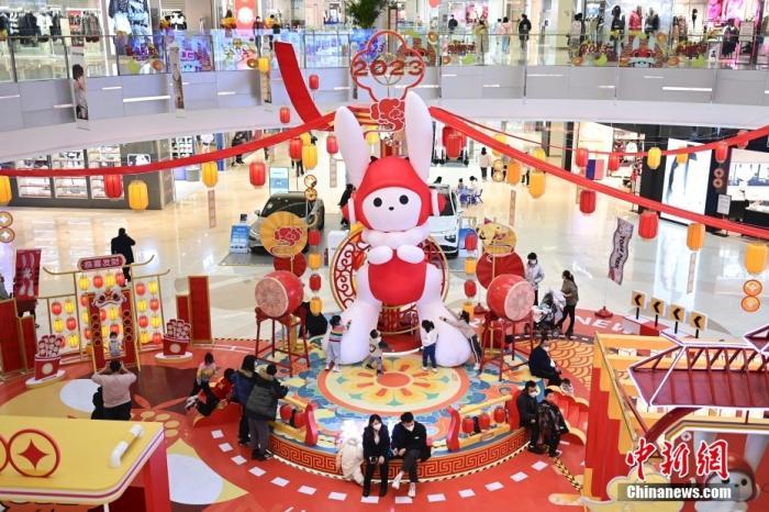 市民在北京一商场内的兔年装饰附近休憩、打卡